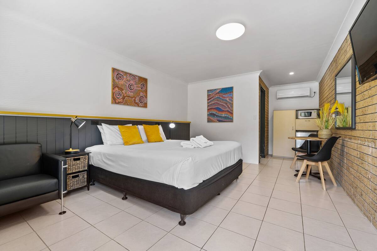 Una habitación de hotel moderna con cama, sofá, escritorio y kitchenette.