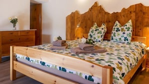 A wooden bed with a leaf-patterned bedspread, a wooden headboard, and two bedside lamps. - Rustico Catcüc by Interhome (Malvaglia)