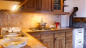 A kitchen with wooden cabinets, a gas stove, and a sink. - Rustico Catcüc by Interhome (Malvaglia)