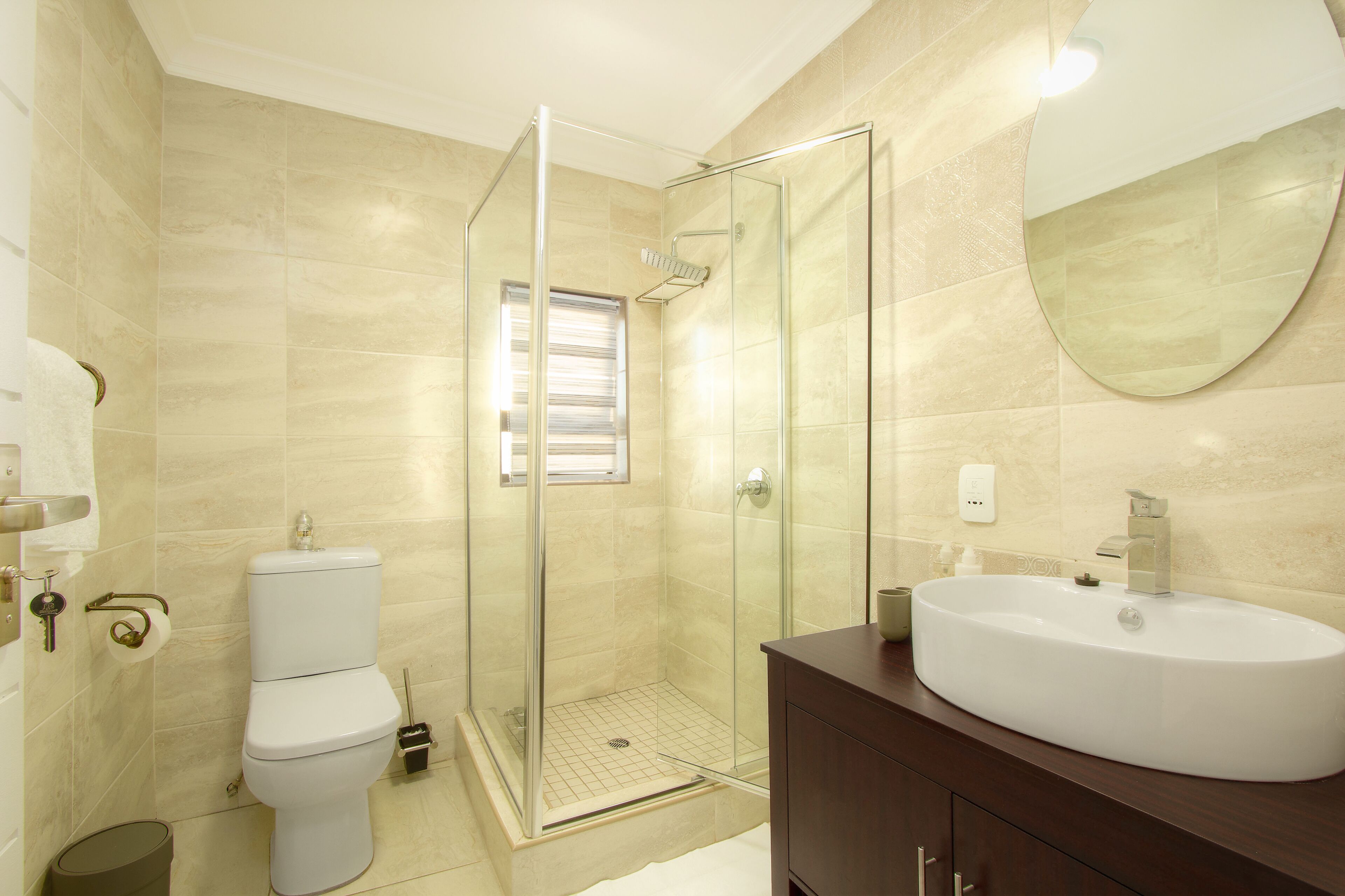 A bathroom with a glass-enclosed shower, a toilet, and a sink with a large mirror.