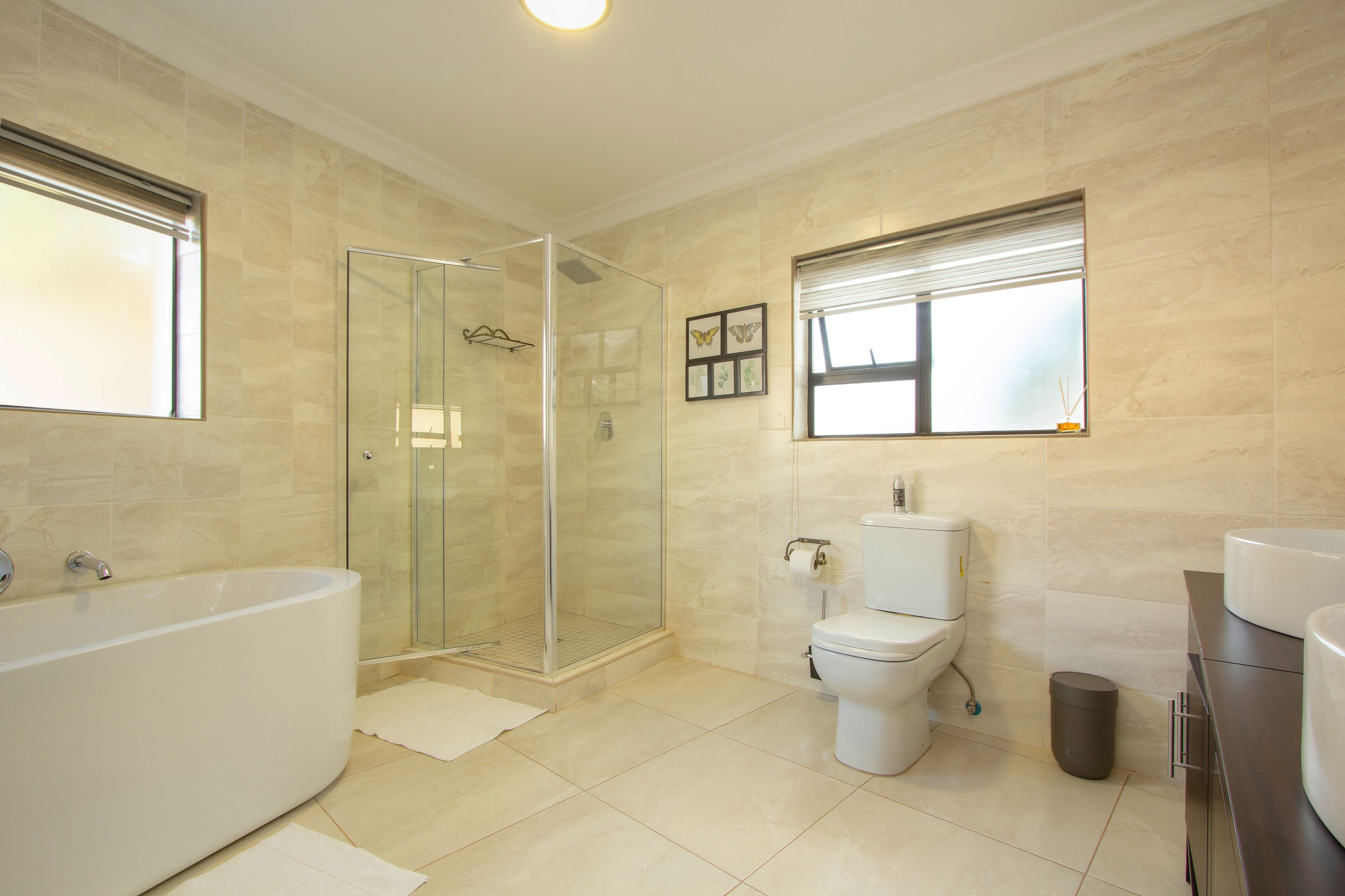 Un baño moderno con ducha acristalada, bañera independiente, inodoro y tocador con lavamanos.