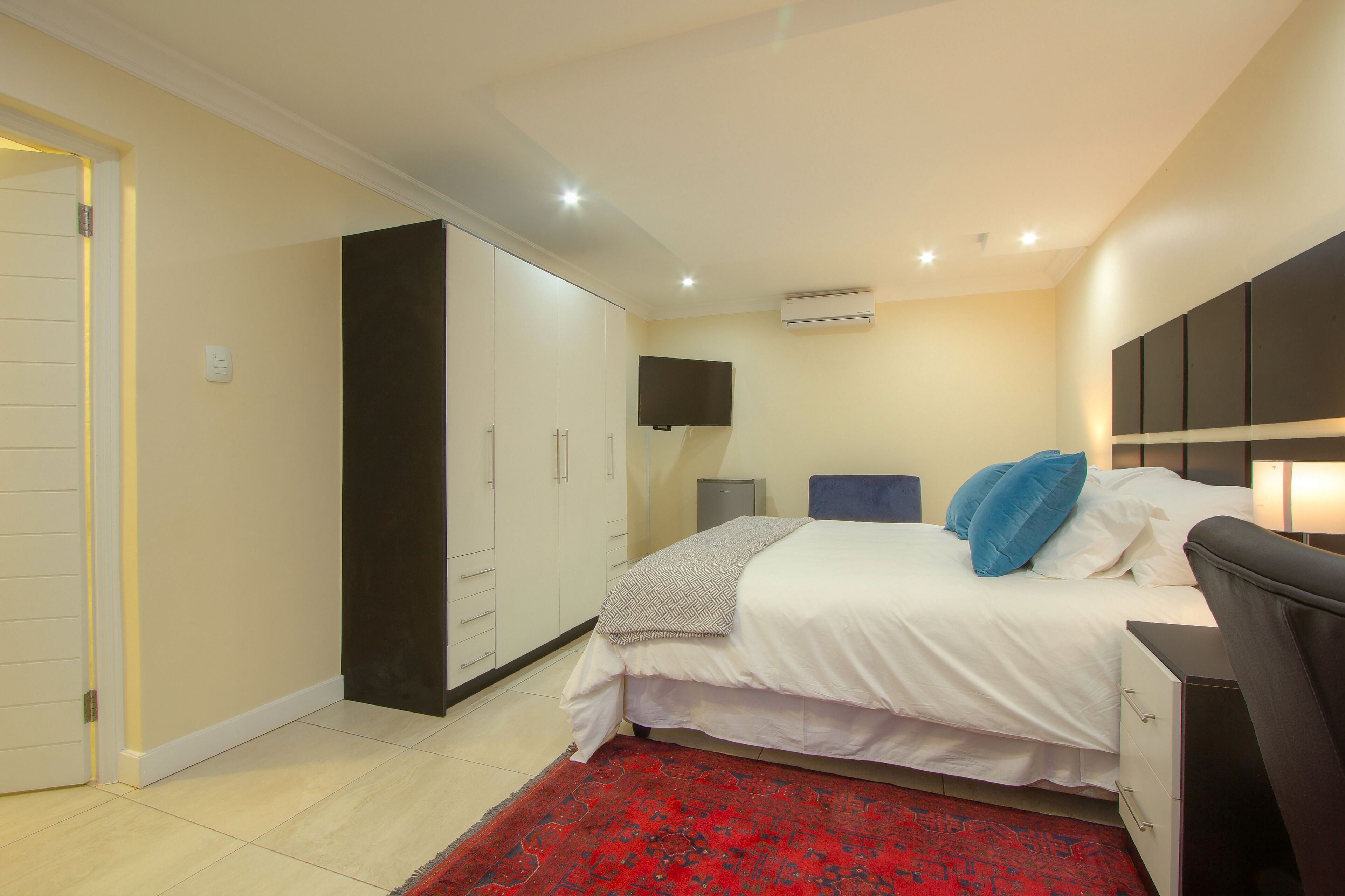 A bedroom with a bed, a wardrobe, a TV, and a desk.