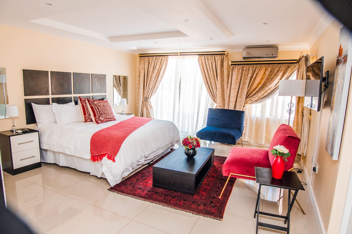 A modern hotel room with a large bed, a desk, a chair, and a TV.