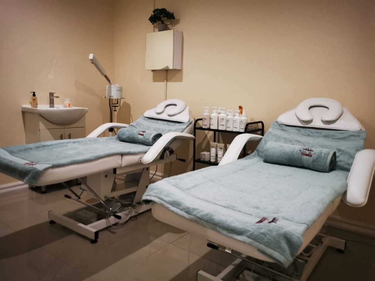 A medical facility with two examination beds, a sink, and a cabinet with medical supplies.