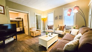 Un salon comprenant un téléviseur, un canapé, des fauteuils, une table basse et une lampe.
