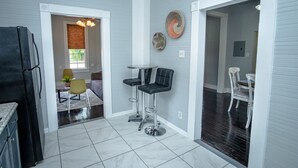 A modern kitchen with a black refrigerator, a dining area with a table and chairs, and a bar area with stools. - Stunning 2br/1ba Historic Pad Few Steps Downtown (San Antonio)