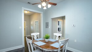 A dining area with a round wooden table, white chairs, and a ceiling fan. - Stunning 2br/1ba Historic Pad Few Steps Downtown (San Antonio)