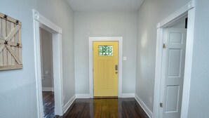 A hallway with a yellow door, white walls, and wooden flooring. - Stunning 2br/1ba Historic Pad Few Steps Downtown (San Antonio)
