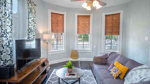 A living room with a TV, a ceiling fan, a sofa, and a coffee table. - Stunning 2br/1ba Historic Pad Few Steps Downtown (San Antonio)