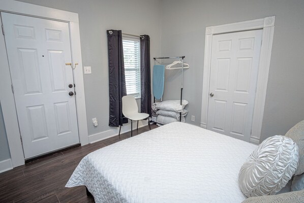 A bedroom with a bed, a chair, a window with curtains, and a door.