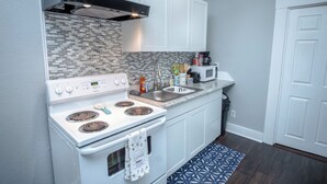 A modern kitchen with white cabinets, a stainless steel range hood, a microwave, and a built-in oven. - Classic 1br/1ba Charming Apt w/ Modern Upgrades (San Antonio)