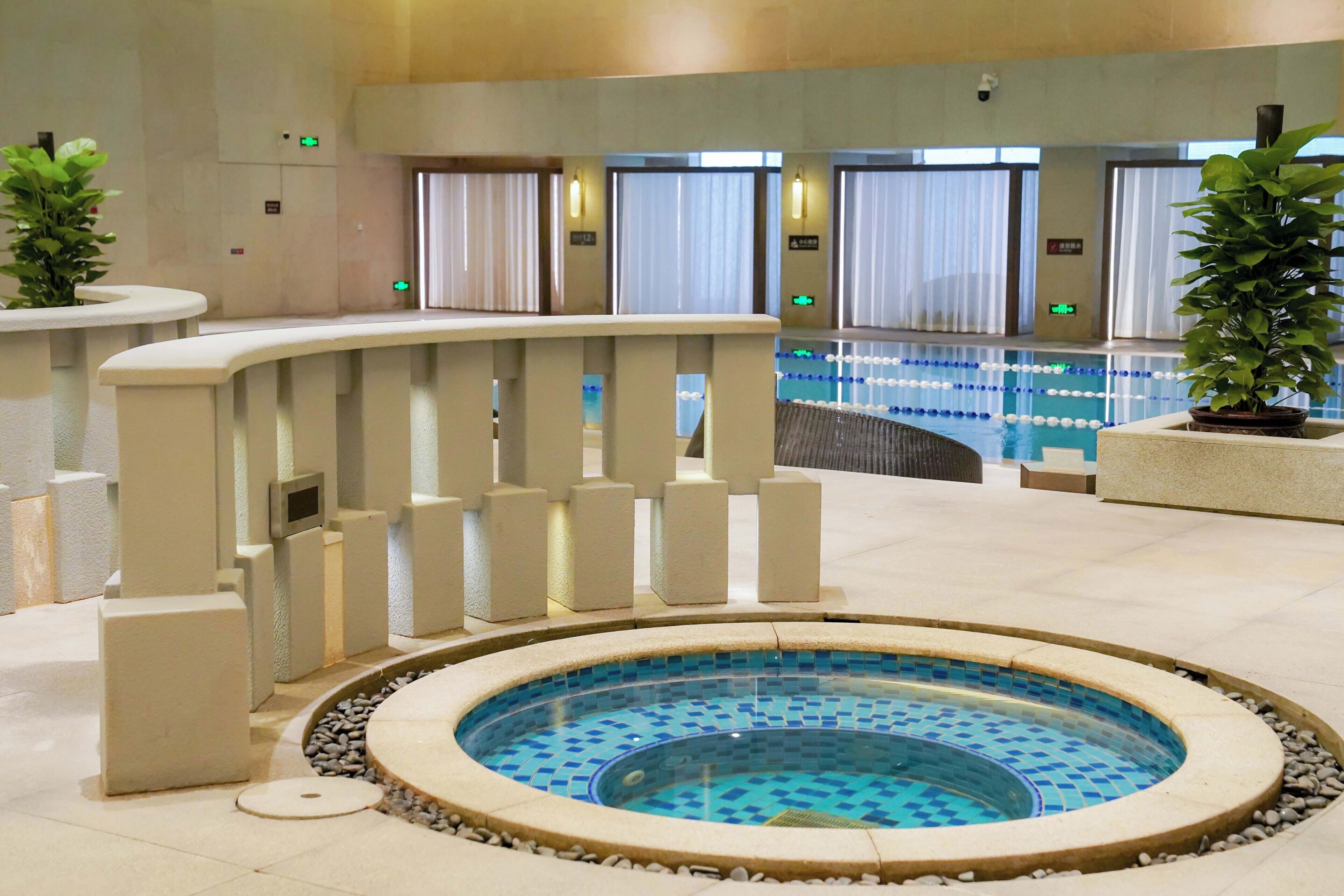 Un área de piscina con un jacuzzi, una zona de estar con barandilla y vistas a la piscina.