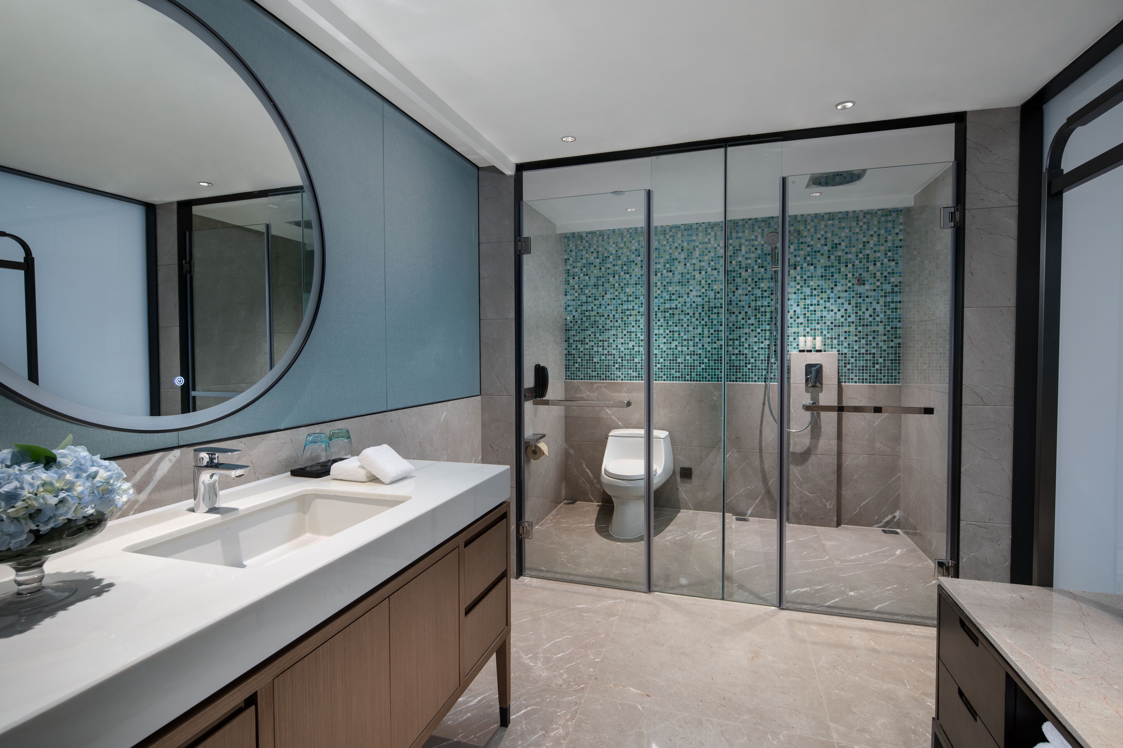 A modern bathroom with a large mirror, two sinks, a glass-enclosed shower, and a tiled backsplash.