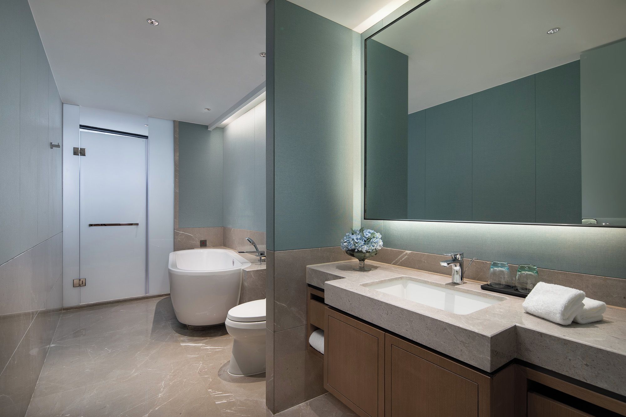 A modern bathroom with a large mirror, a bathtub, and a sink.