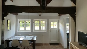Un comedor con una mesa y sillas, un televisor y una puerta que da a otra habitación.