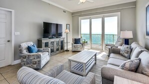 Un salón amplio con televisor, asientos cómodos y un balcón con vistas.