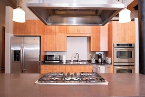 Een moderne keuken met roestvrijstalen apparatuur, houten keukenkastjes, een gasfornuis en een magnetron.