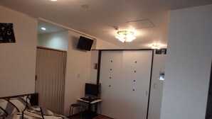 A bedroom with a bed, a desk, a TV, and a wardrobe.