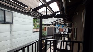 A covered outdoor area with a metal railing, a white wall, and a view of a building in the background.