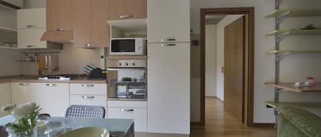 A modern kitchen with white cabinets, a microwave, an oven, and a dining area with a table set for two.