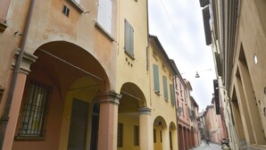 Eine enge Straße mit Gebäuden, die Rundbogenportale und Balkone aufweisen.