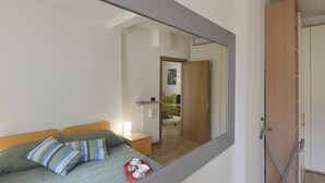Ein Schlafzimmer mit einem Bett, einem Nachttisch, einem Spiegel und einem Kleiderschrank.