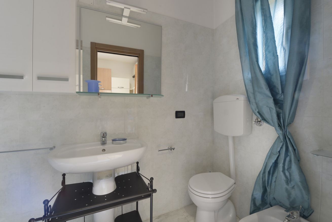 Een badkamer met een wit wastafel, een spiegel, een toilet en een douchegordijn.