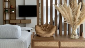 Ein modernes Wohnzimmer mit einer Couch, einem Holztischchen, einem Fernseher und einer dekorativen Vase mit Pampasgras.