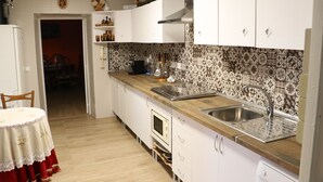 Una cocina con armarios blancos, encimera de madera, pileta de acero inoxidable y azulejos decorativos en la pared.