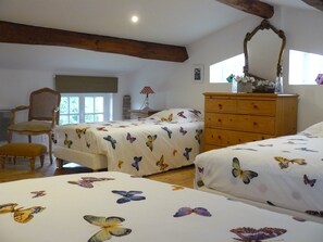 A bedroom with two beds, a wooden dresser, a chair, and a window with natural light.
