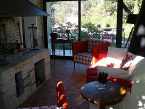 A cozy outdoor seating area with a fireplace, a table with a glass, and a view of greenery. - 19th-century building, 3 stars *** (Arsac)