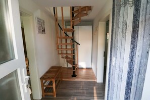 Eine Wendeltreppe mit Holzsitzgelegenheiten und schwarzen Geländern, eine Holzbank und eine Tür mit Milchglasfüllung.