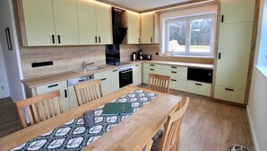 Une cuisine de taille réduite avec des meubles de couleur vert clair, une table à manger en bois et une fenêtre qui laisse entrer la lumière naturelle.