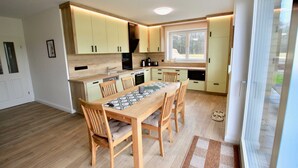 Une cuisine moderne avec des meubles en bois, une table à manger avec des chaises et une grande fenêtre qui laisse entrer la lumière naturelle.