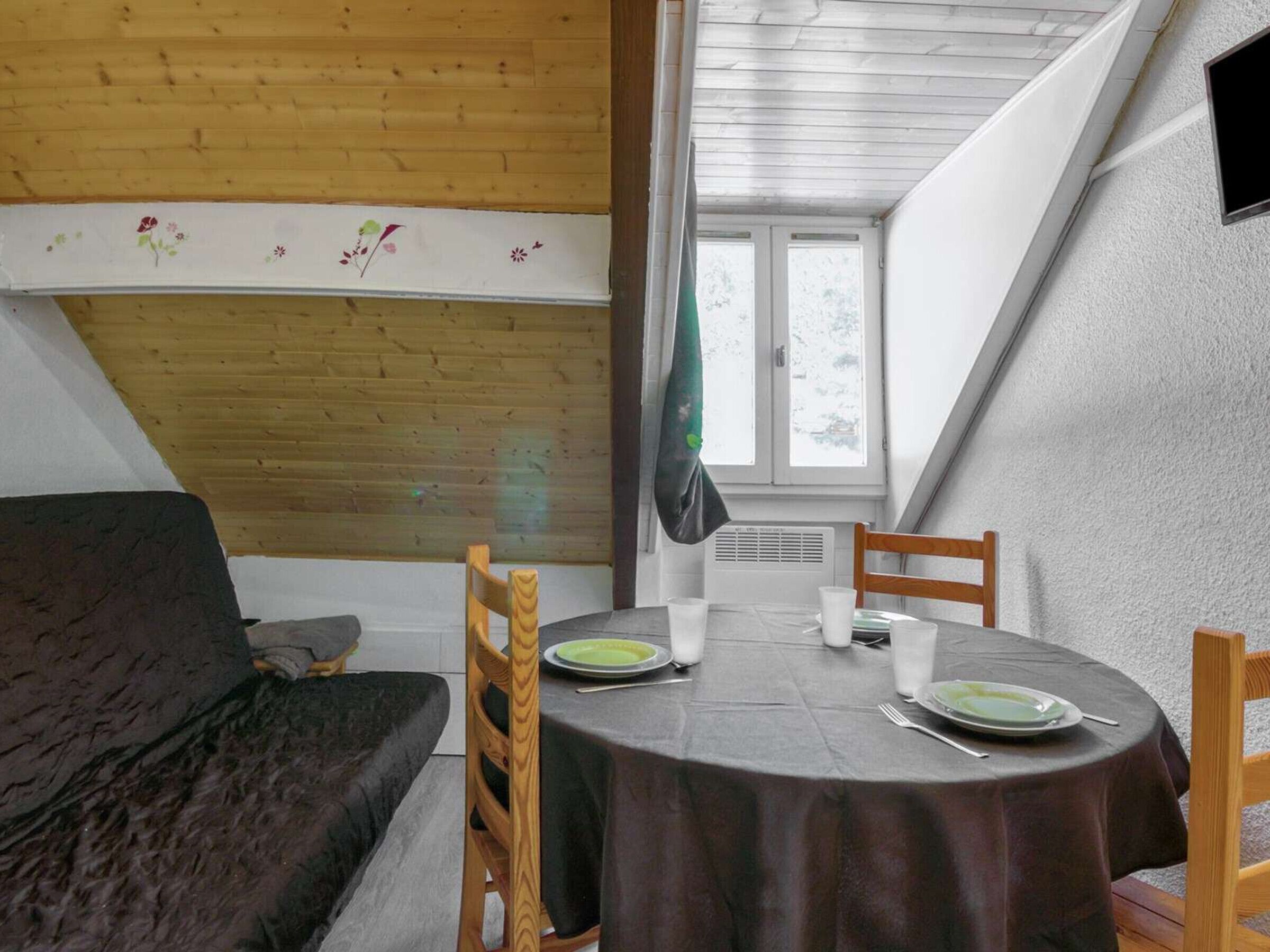 En matplats med ett runt bord, stolar och en svart duk. Det finns ett fönster med utsikt över träd utanför.