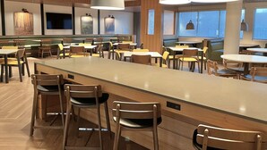 Um restaurante moderno com um balcão extenso, diversas áreas de estar e iluminação pendente.