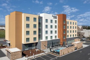 A multi-story hotel with a modern design, featuring a pool area and a parking lot.