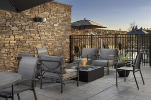 Une terrasse extérieure avec des murs en pierre, un foyer et des meubles modernes.