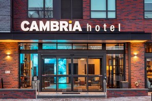 The exterior of the CAMBRIA hotel with a modern design, featuring large glass doors and a brick facade. - Cambria Hotel Washington D.C. Navy Yard Riverfront (Washington)
