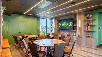 A conference room with a large table and chairs, a television screen, and a view of buildings outside.