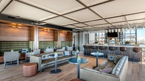 A modern bar area with leather seating, round tables, and a city view. - Cambria Hotel Washington D.C. Navy Yard Riverfront (Washington)