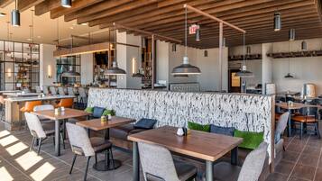A modern restaurant with wooden beams, pendant lighting, and a mix of booth and table seating.