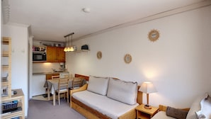 Un ambiente compatto con angolo cottura, divano letto e zona pranzo.
