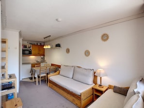 Een ruimtelijke leefruimte met een kitchenette, een slaapbank en een eethoek.
