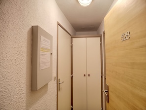 A hallway with a wooden door marked with the number 528, a white door with a notice on the wall, and a light fixture on the ceiling.