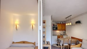 Una camera compatta con un letto, una scrivania, una sedia, un tavolino e angolo cottura.