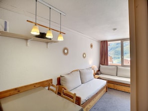 Een gezellige kamer met een houten bank, een klein tafeltje en een raam met gordijnen.