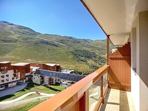 Un balcon offrant une vue sur un paysage montagneux, un bâtiment équipé de panneaux solaires et un télésiège.