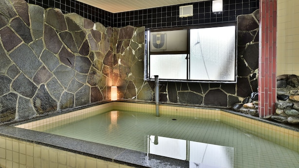 A stone-walled indoor pool with a tiled floor, a fan, and a window. - Guest House Takenoya (Omachi)