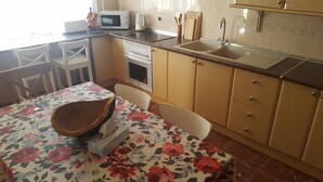 Une cuisine équipée d’un four à micro-ondes, d’une cuisinière, d’un évier et d’une table recouverte d’une nappe à motifs floraux.